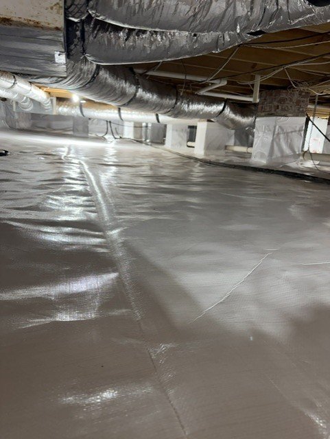 Crawlspace with white vapor barrier encapsulation and HVAC ductwork installed