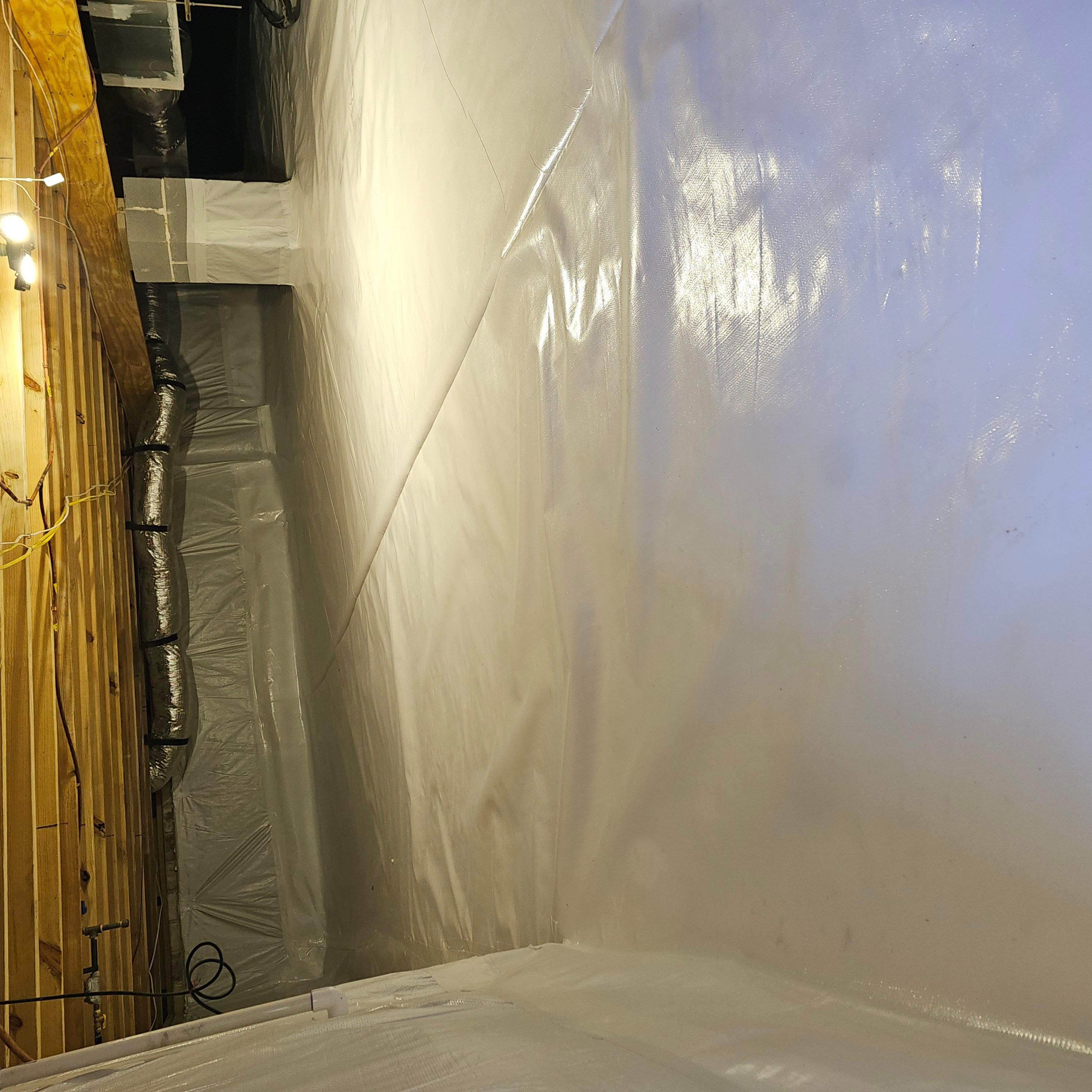 Crawlspace with white vapor barrier encapsulation and sealed HVAC ductwork installed