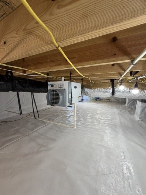 Encapsulated crawlspace with vapor barrier, HVAC units, and yellow electrical conduit