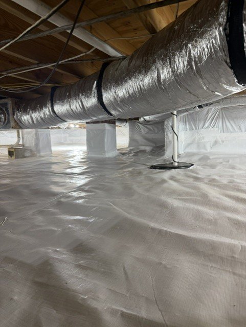 Crawlspace with white vapor barrier flooring and silver insulated ductwork overhead