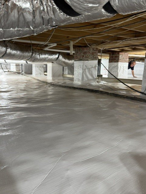 Crawlspace with white vapor barrier, sealed ductwork, and support posts in encapsulation project