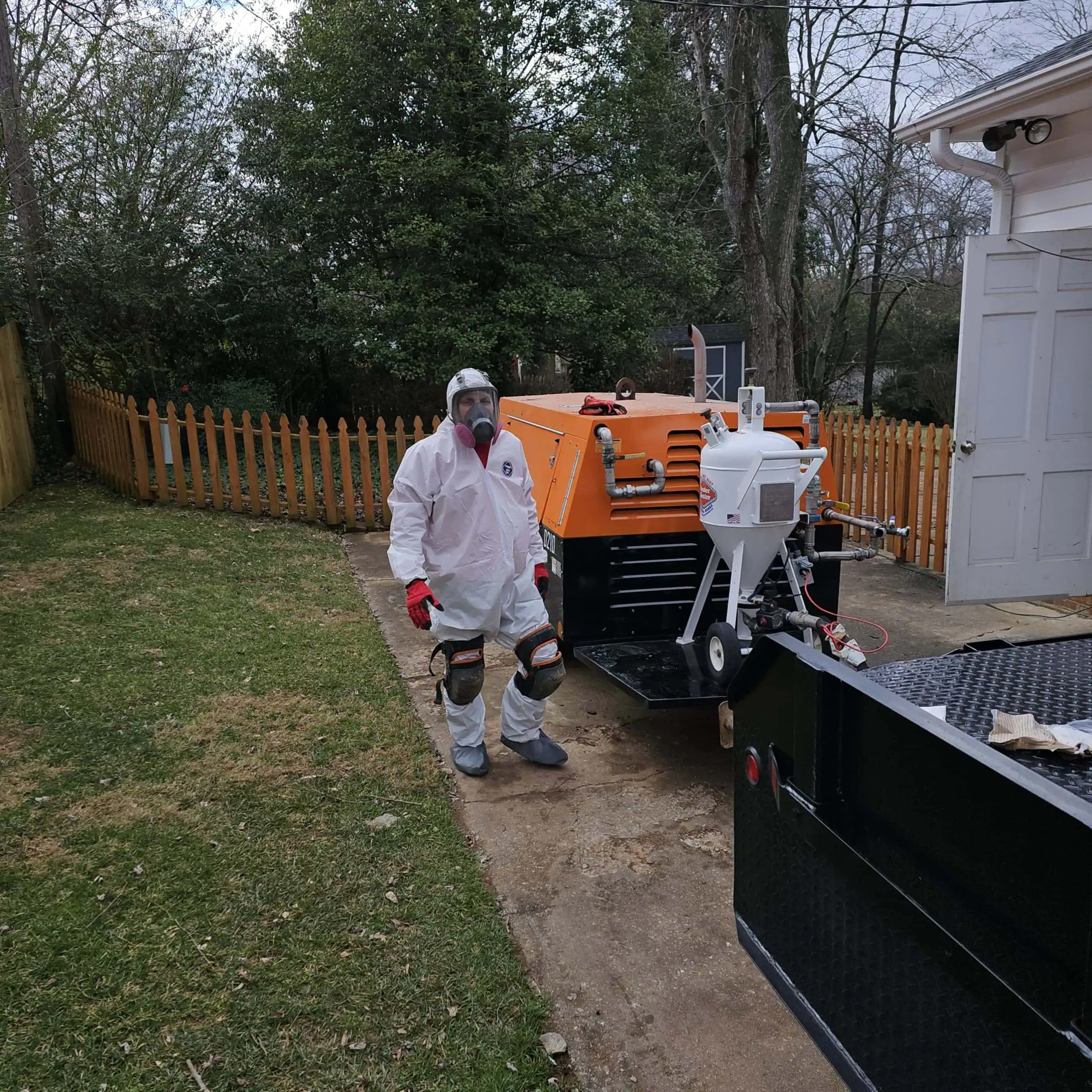 Technician in protective gear with air purification equipment outdoors.