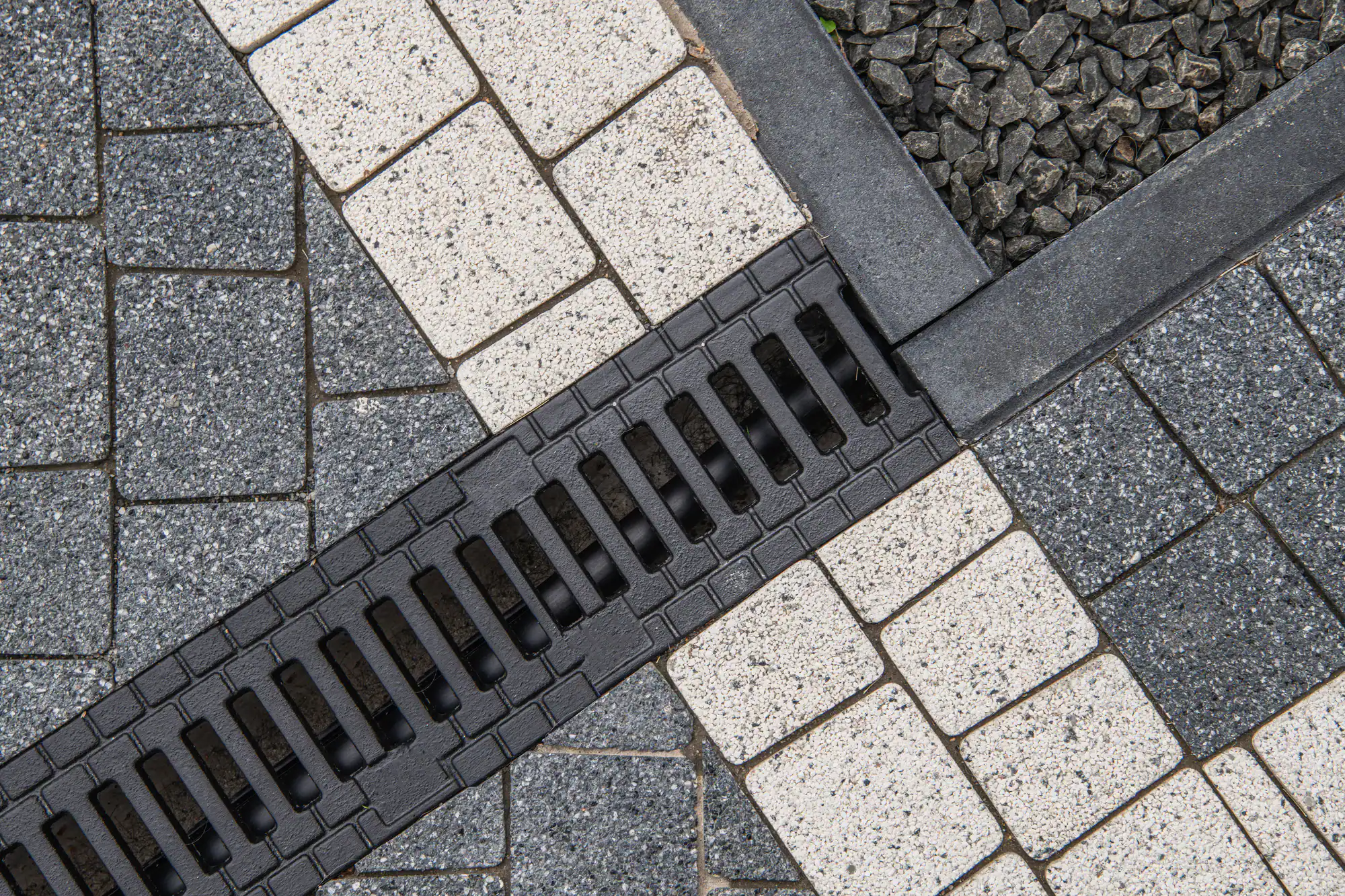 Close-up of gray and white paving stones with a black drainage grate in Guilford County, NC.